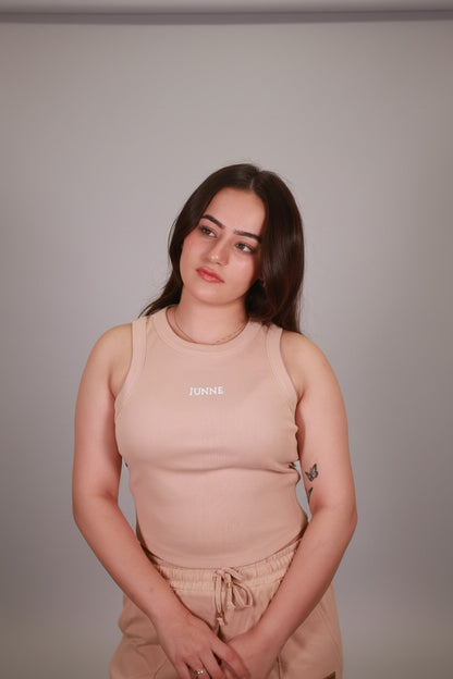 Woman wearing a beige dress with 'Chanel' branding against a neutral background