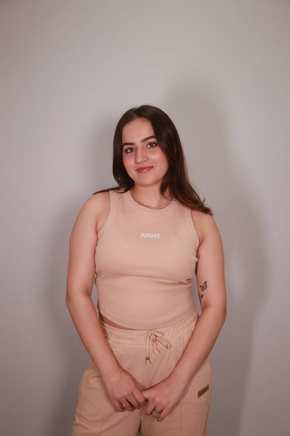 Woman wearing a beige tank top with text in a neutral setting